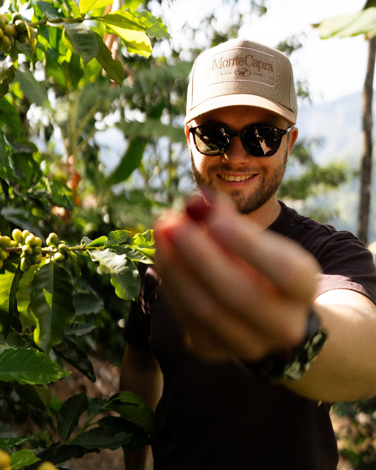 Hombre sonriendo mientras muestra una cereza de café recién cosechada