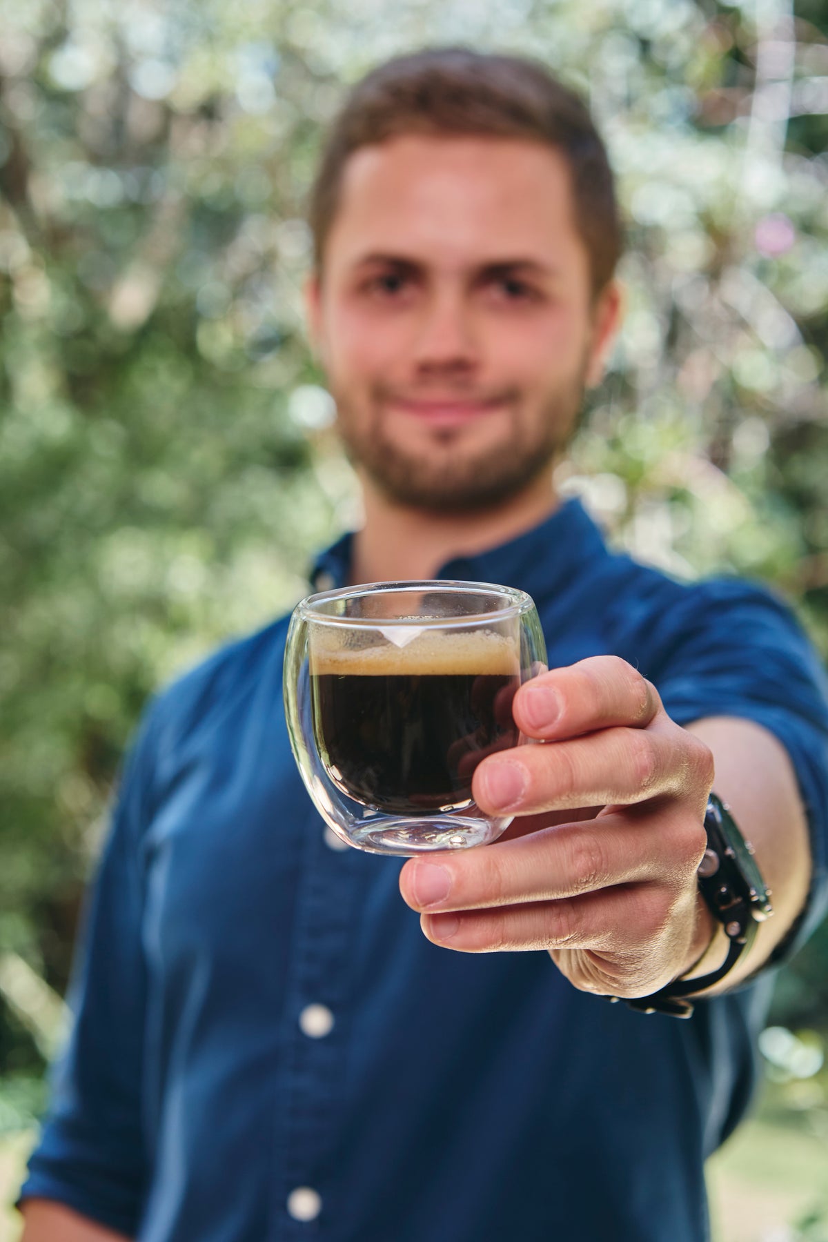 Recolectora sonriente sosteniendo un balde con cerezas de café en el cafetal