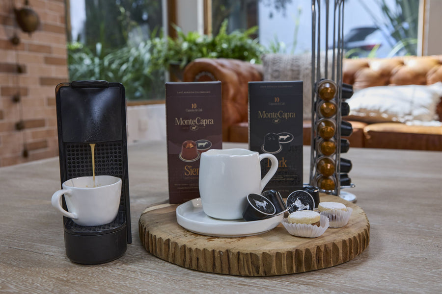 Cafetera, cajas Monte Capra y tazas listas sobre una mesa de madera