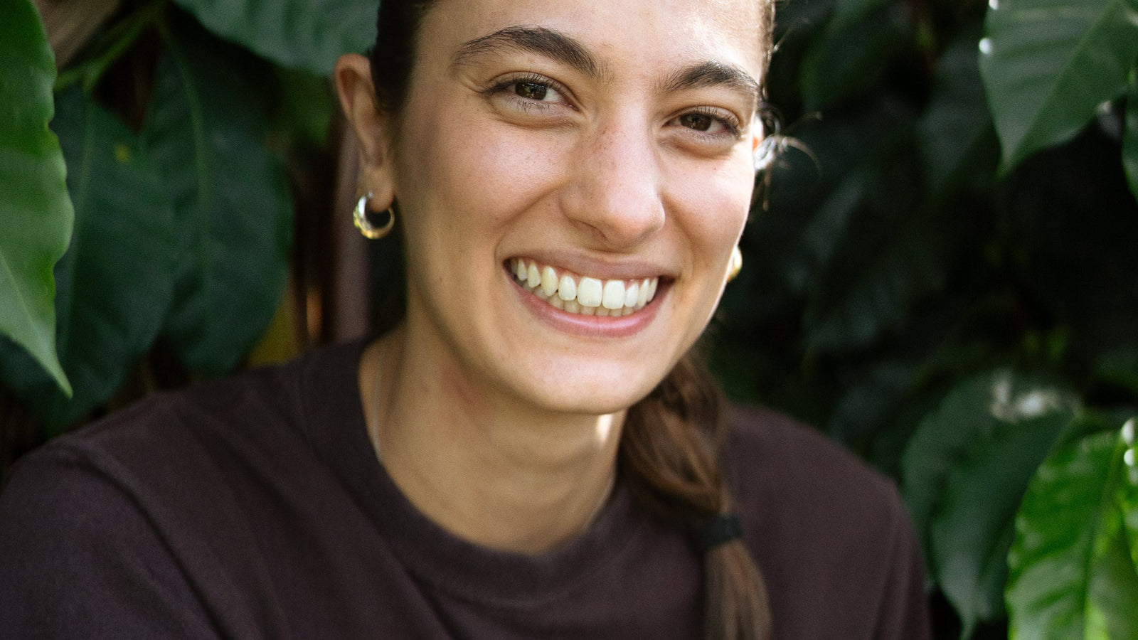 Mujer sonriendo entre plantas de café